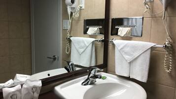 Un baño con lavamanos, espejo, toallero, secador de pelo y teléfono.