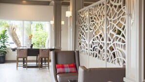 Um interior moderno com área de estar, divisória decorativa e vista para o verde lá fora.