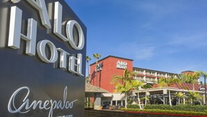 Exterior do hotel ALO, com vista nítida da entrada e palmeiras ao redor.
