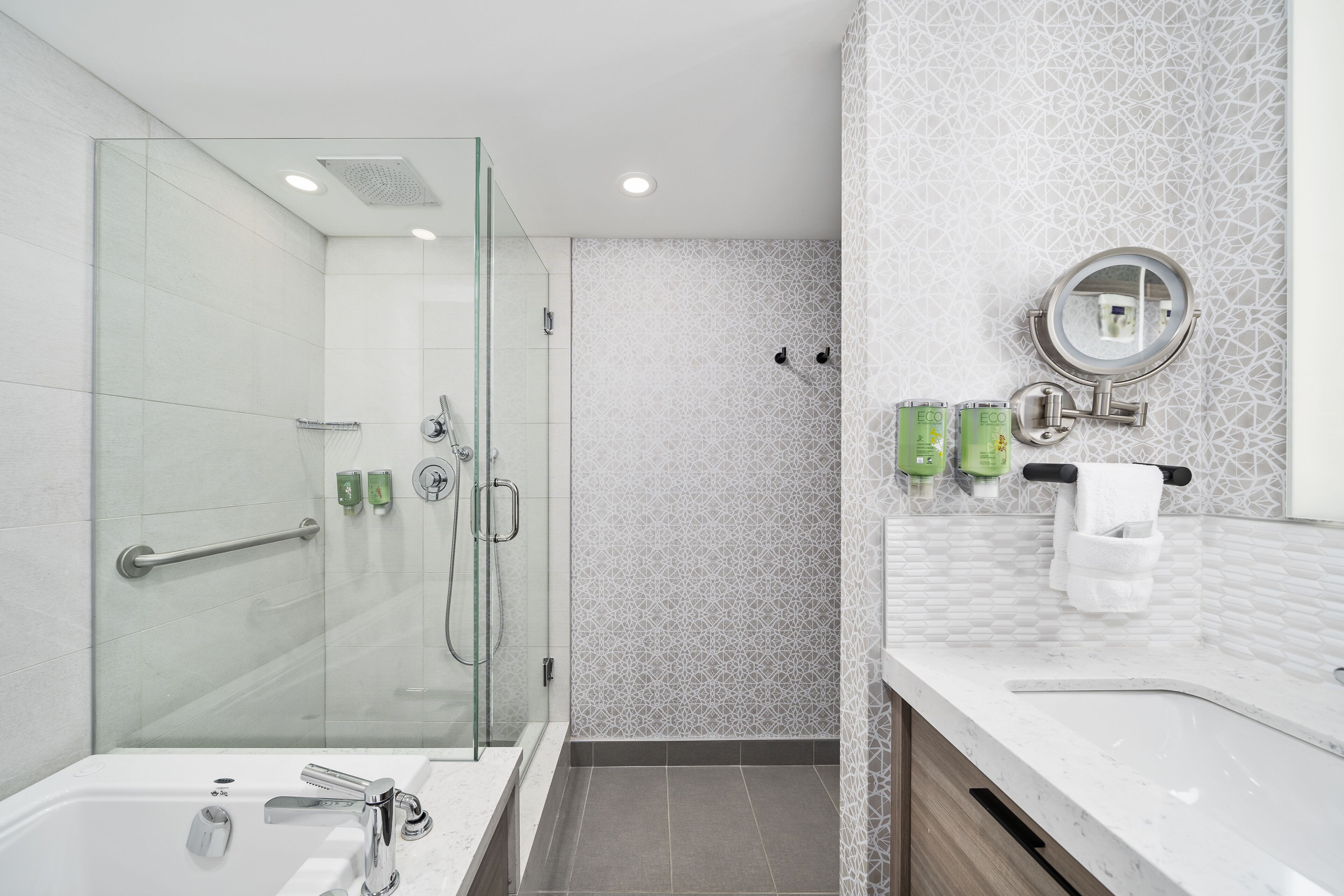 A modern bathroom with a glass-enclosed shower, a standalone bathtub, and a vanity with a mirror.