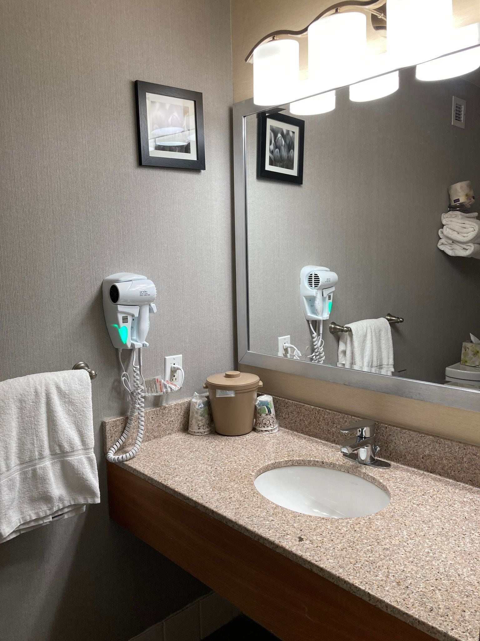A bathroom with a sink, towel rack, hair dryer, and a mirror.