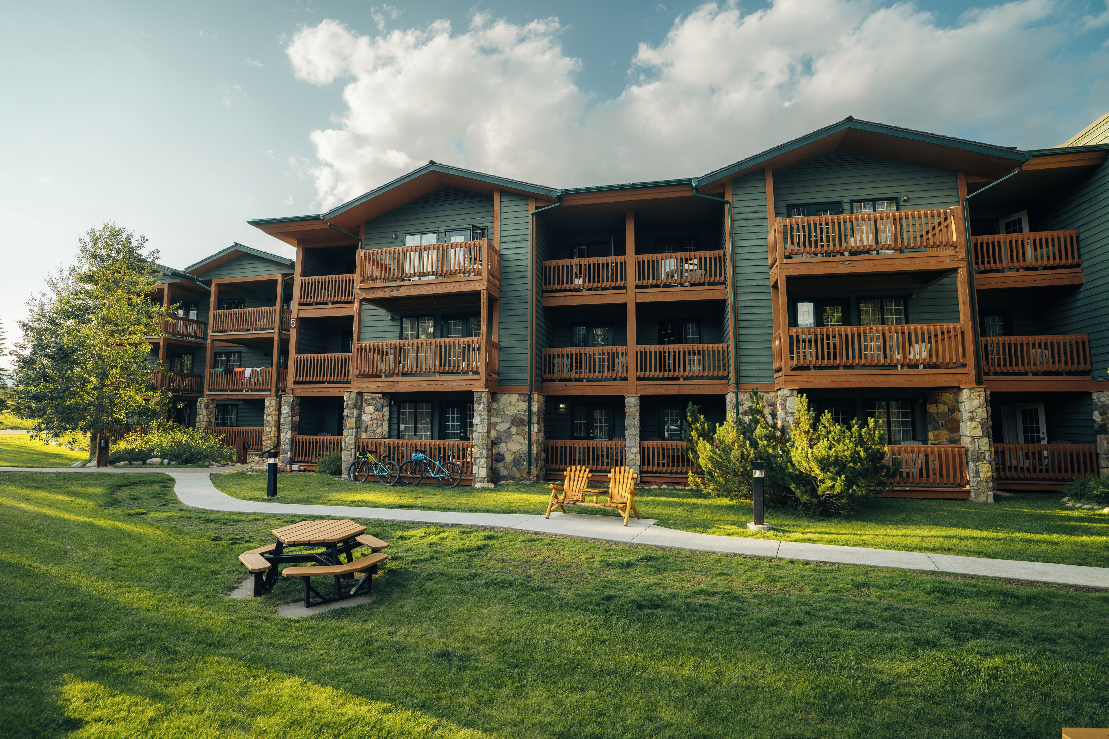 A multi-story hotel with balconies, stone accents, and a picnic area.