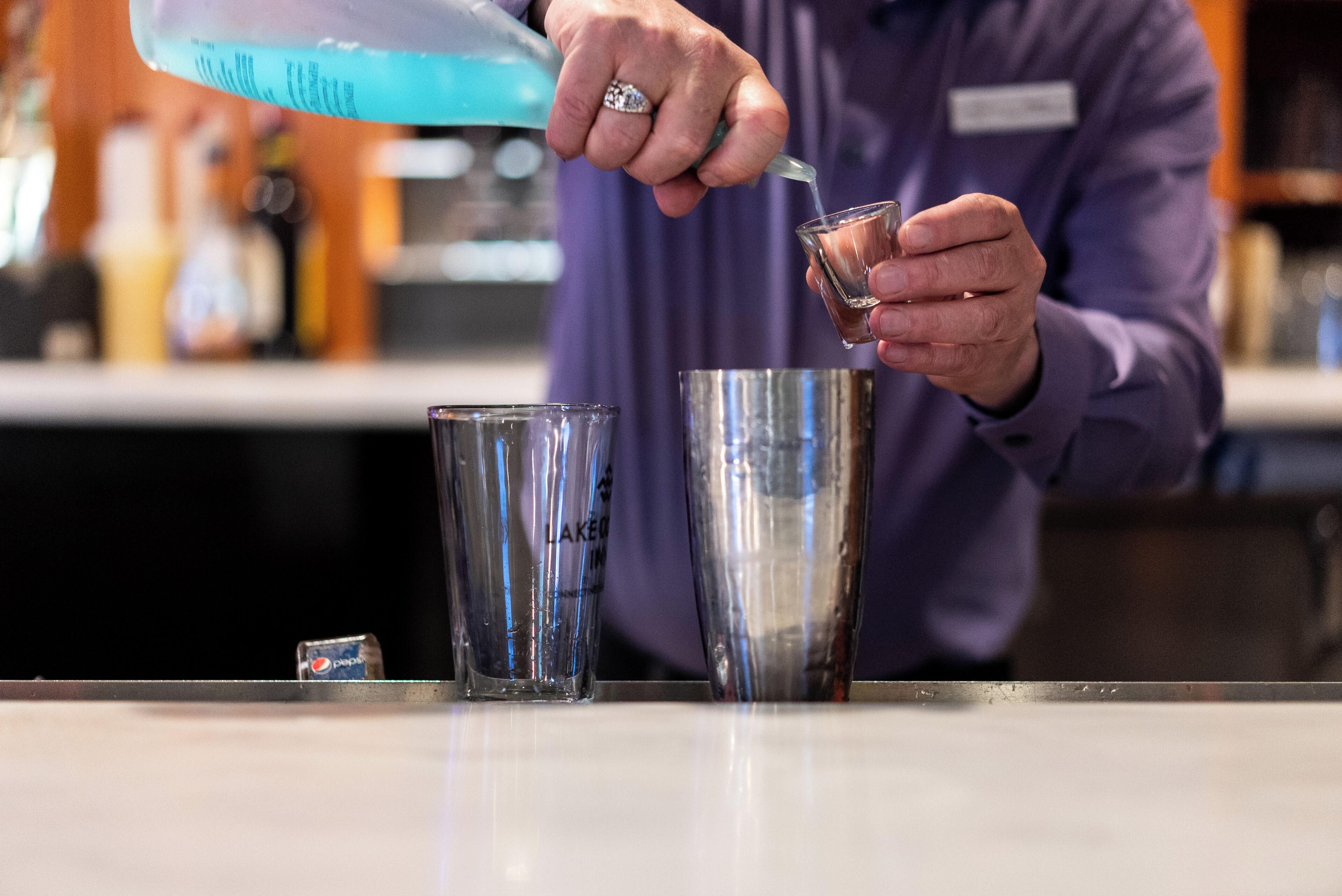 A person pouring a blue liquid into a glass.