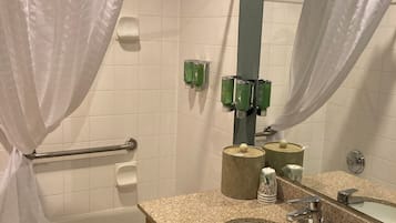 A bathroom with a bathtub, a sink, a mirror, and a shower curtain.