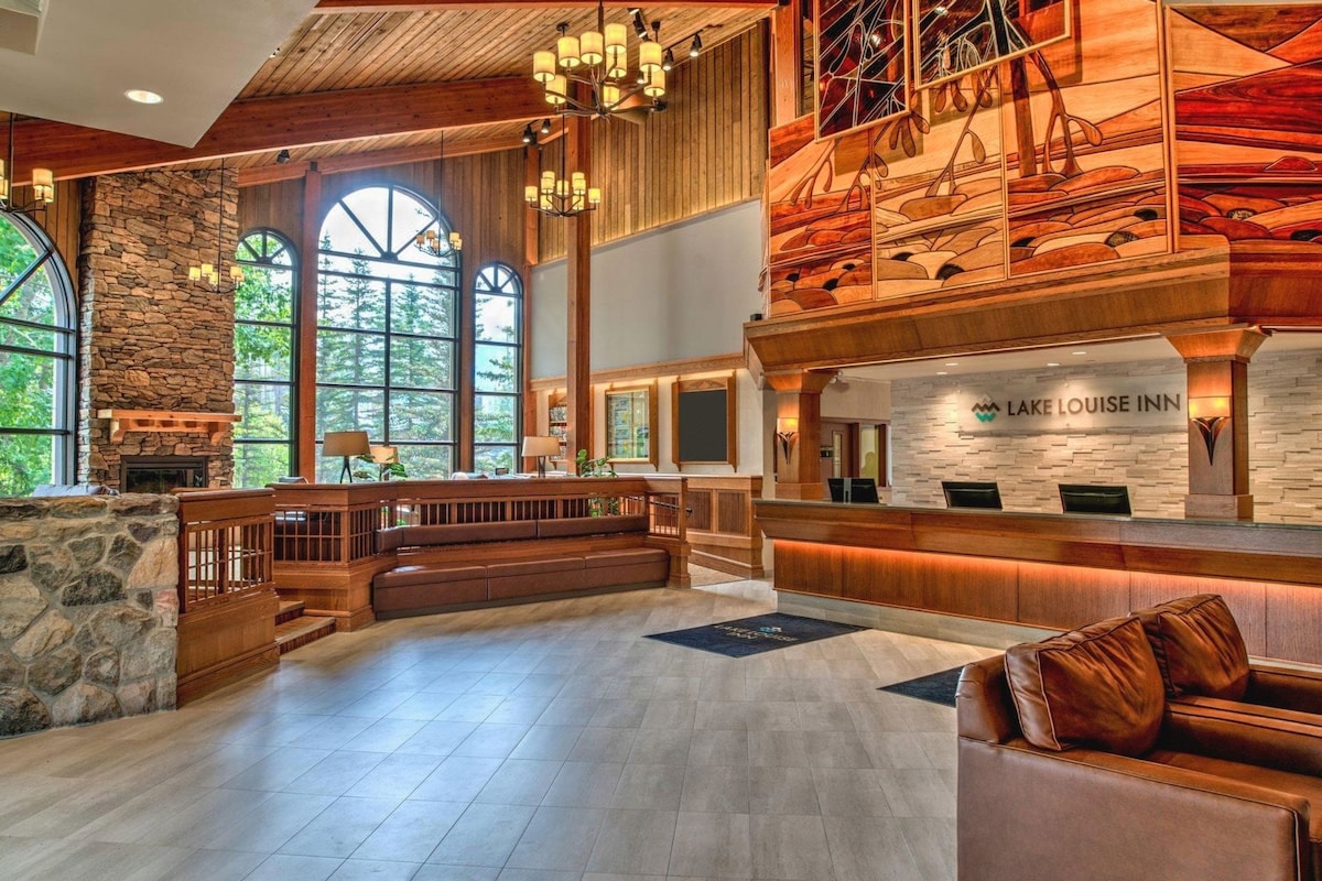 A spacious lobby with a stone fireplace, a reception desk, and a seating area with a view of the outdoors.