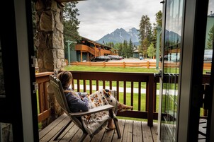 A wooden deck with a stone pillar, a bench, and a view of a mountain range.