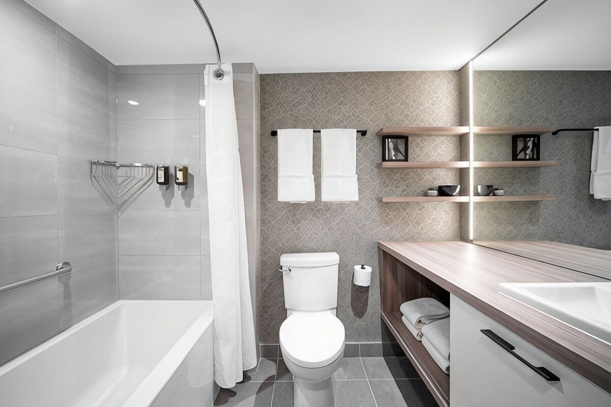 A modern bathroom with a bathtub, toilet, and vanity.