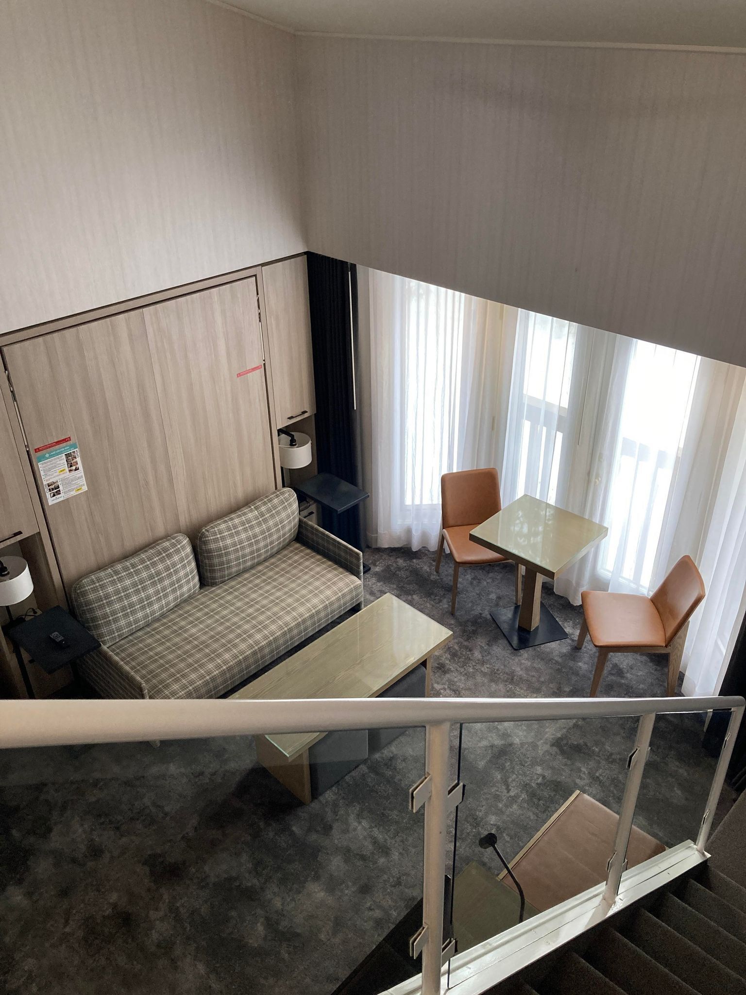 Een hotelkamer met een bank, een tafeltje, twee stoelen, een bureau en een bed.
