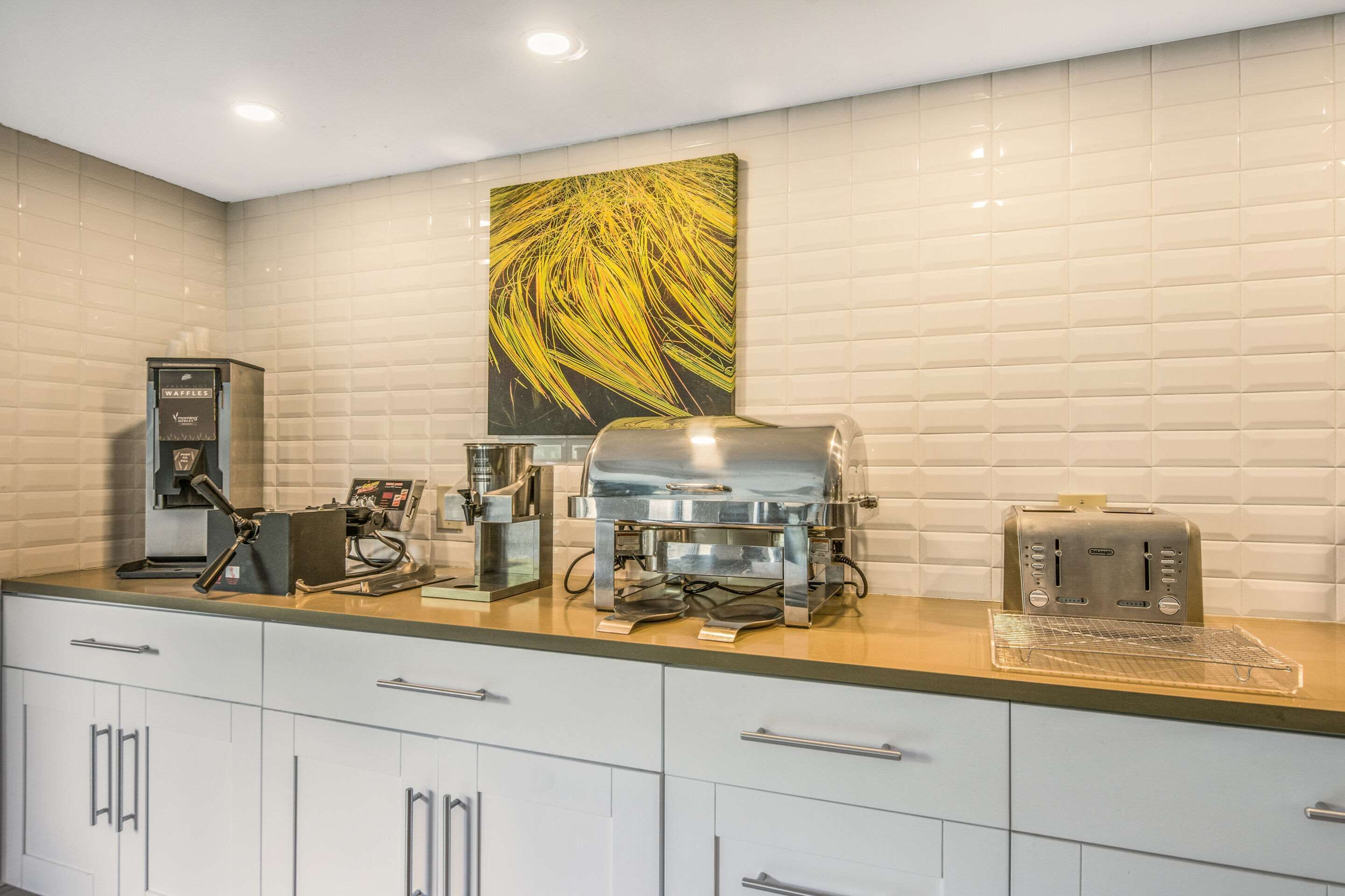 A kitchenette with a waffle maker, coffee maker, and toaster on the counter.
