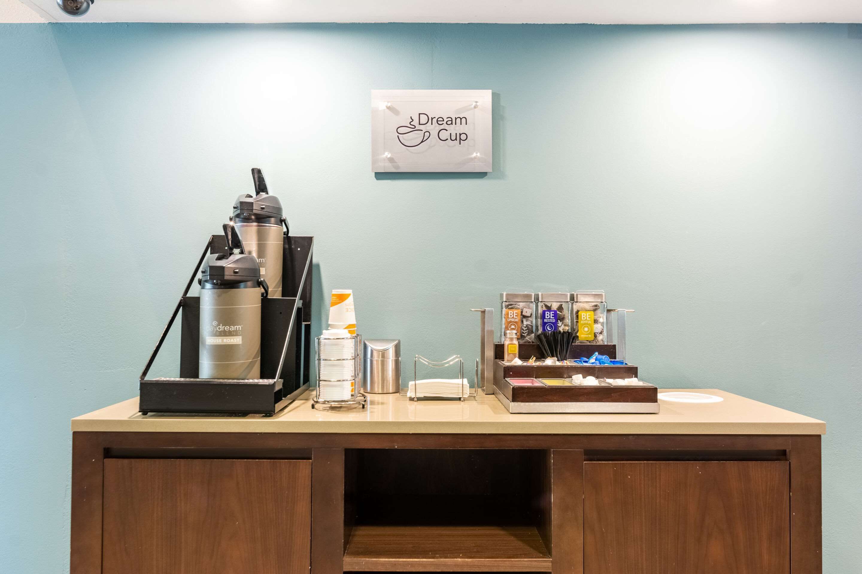 A coffee station with a coffee machine, cups, and a sign that reads "Dream Cup".