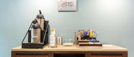 A coffee station with a coffee machine, cups, and a sign that reads "Dream Cup".
