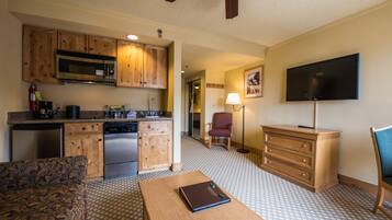 Un espacio habitable compacto con kitchenette, comedor, televisor y suelo estampado.