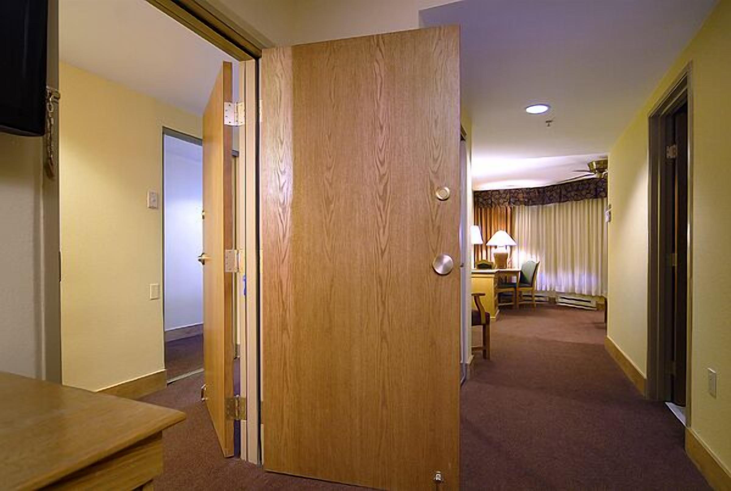 A hotel room with a wooden door, a small table, and a lamp.