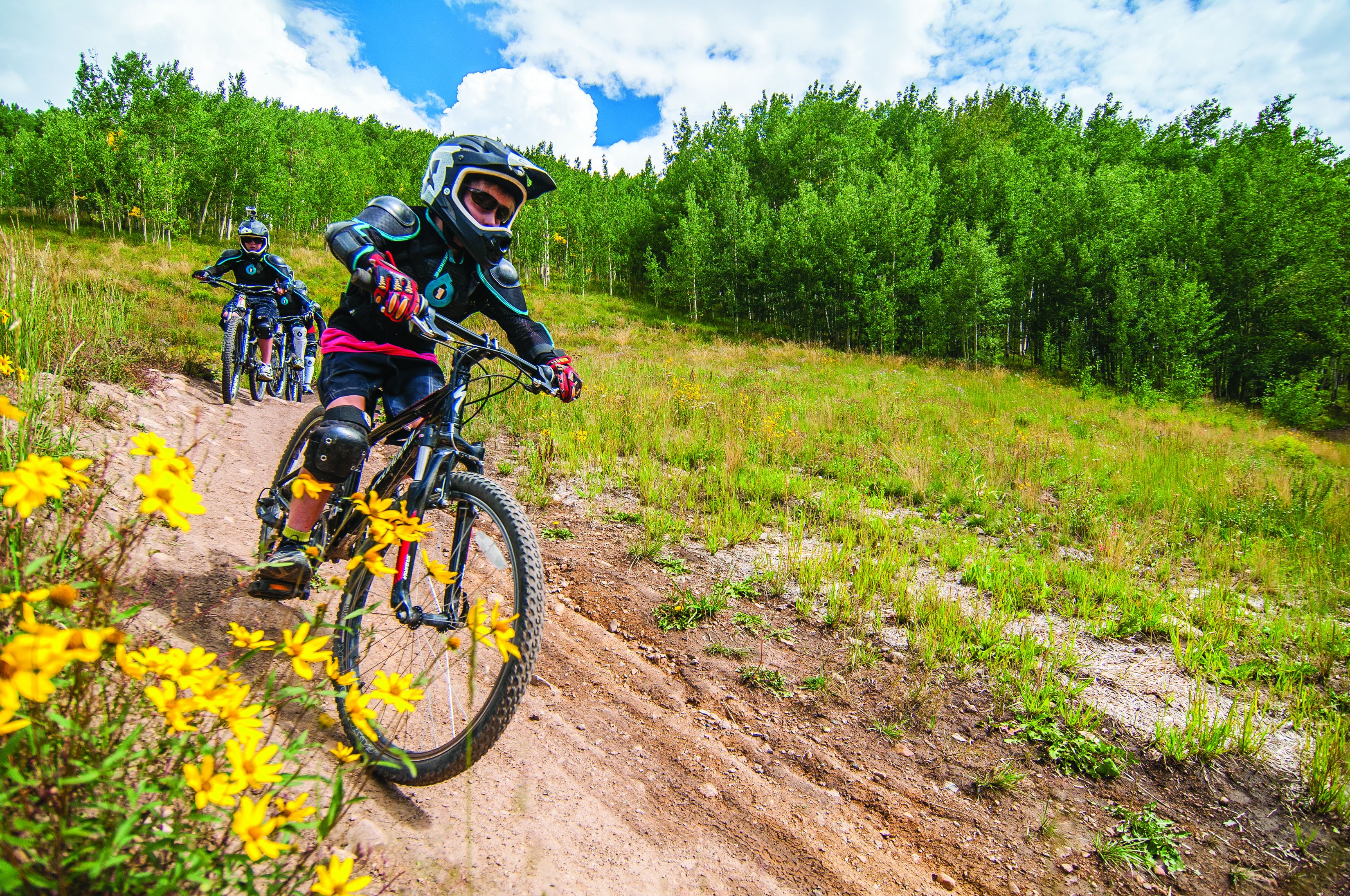 A dirt bike trail with riders in protective gear.