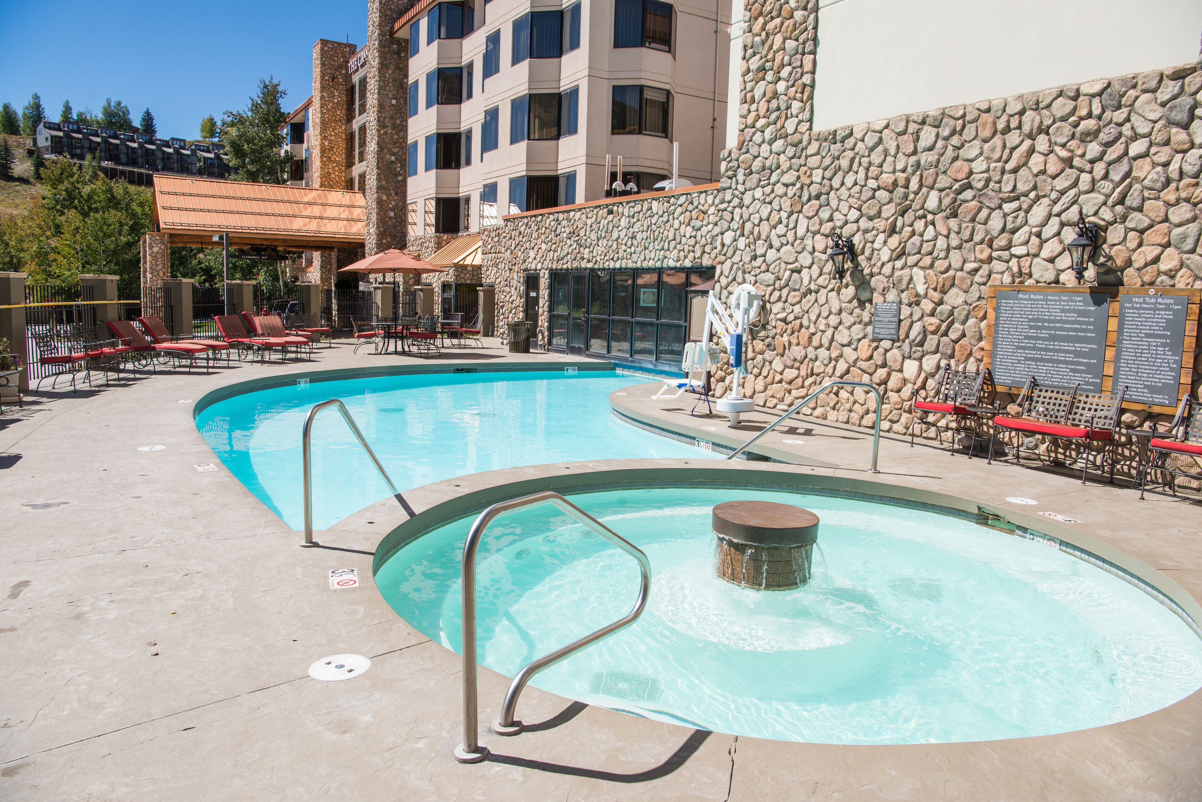 A swimming pool with lounge chairs and a stone wall.