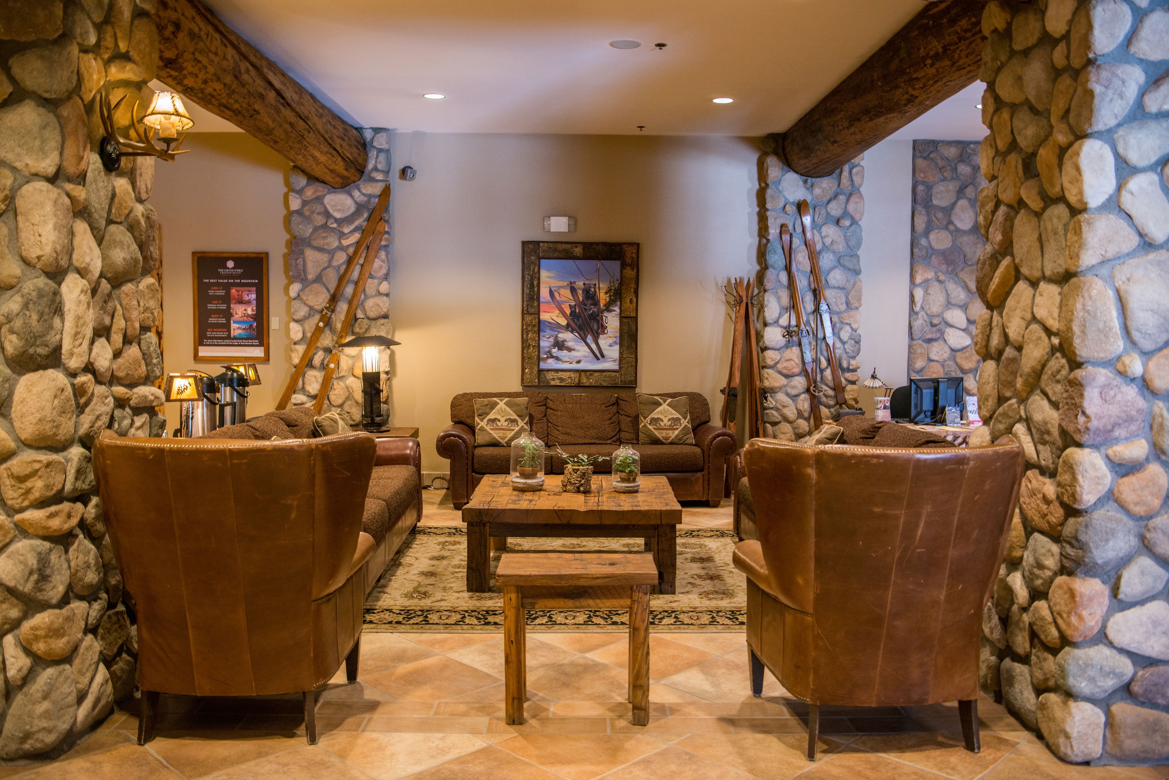 A stone-walled lounge area with leather armchairs, a wooden coffee table, and a sofa.