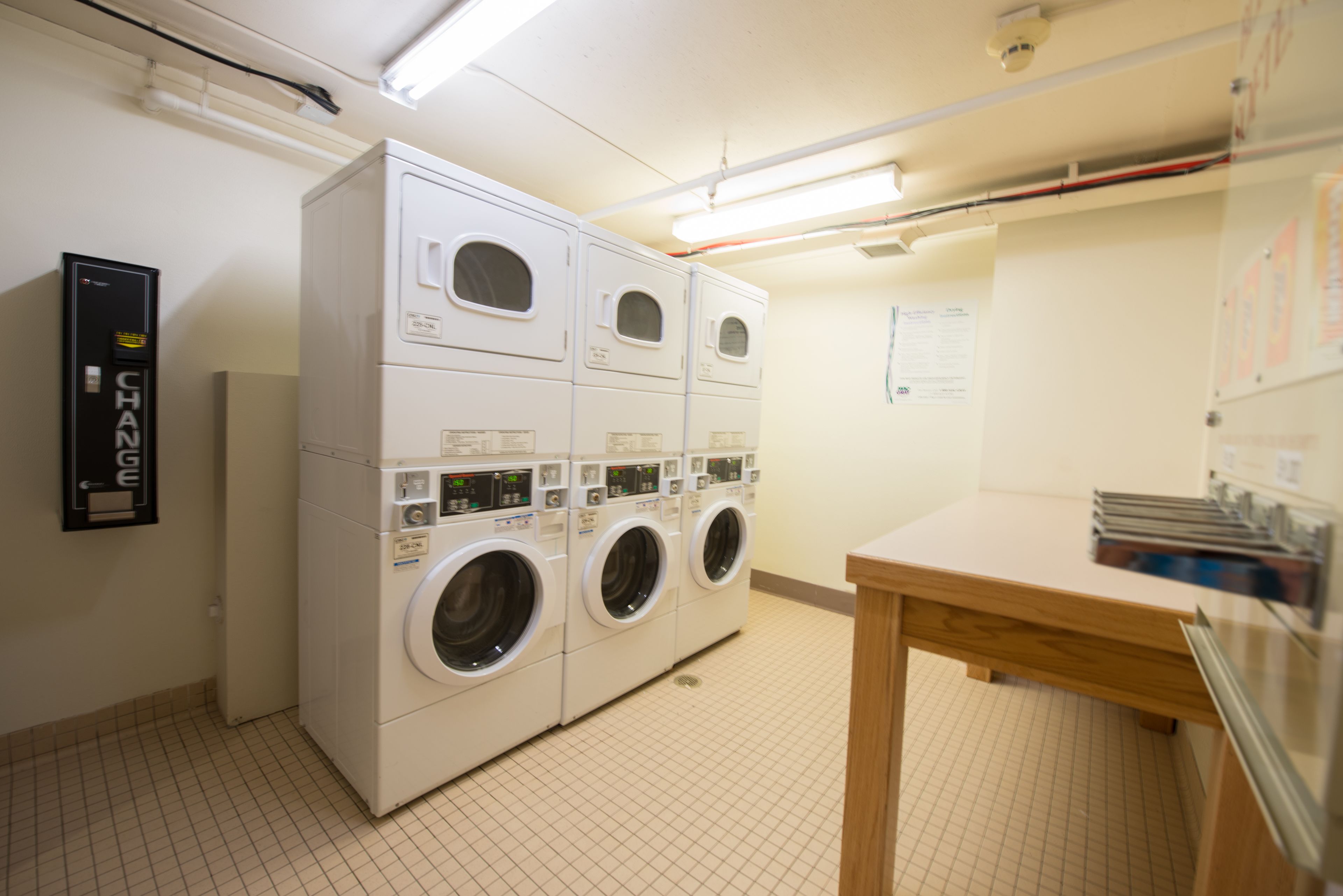 A laundry room with four stacked washing machines and a wooden table.