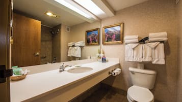 A modern bathroom with a large mirror, a sink, a toilet, and towels hanging on a rack.
