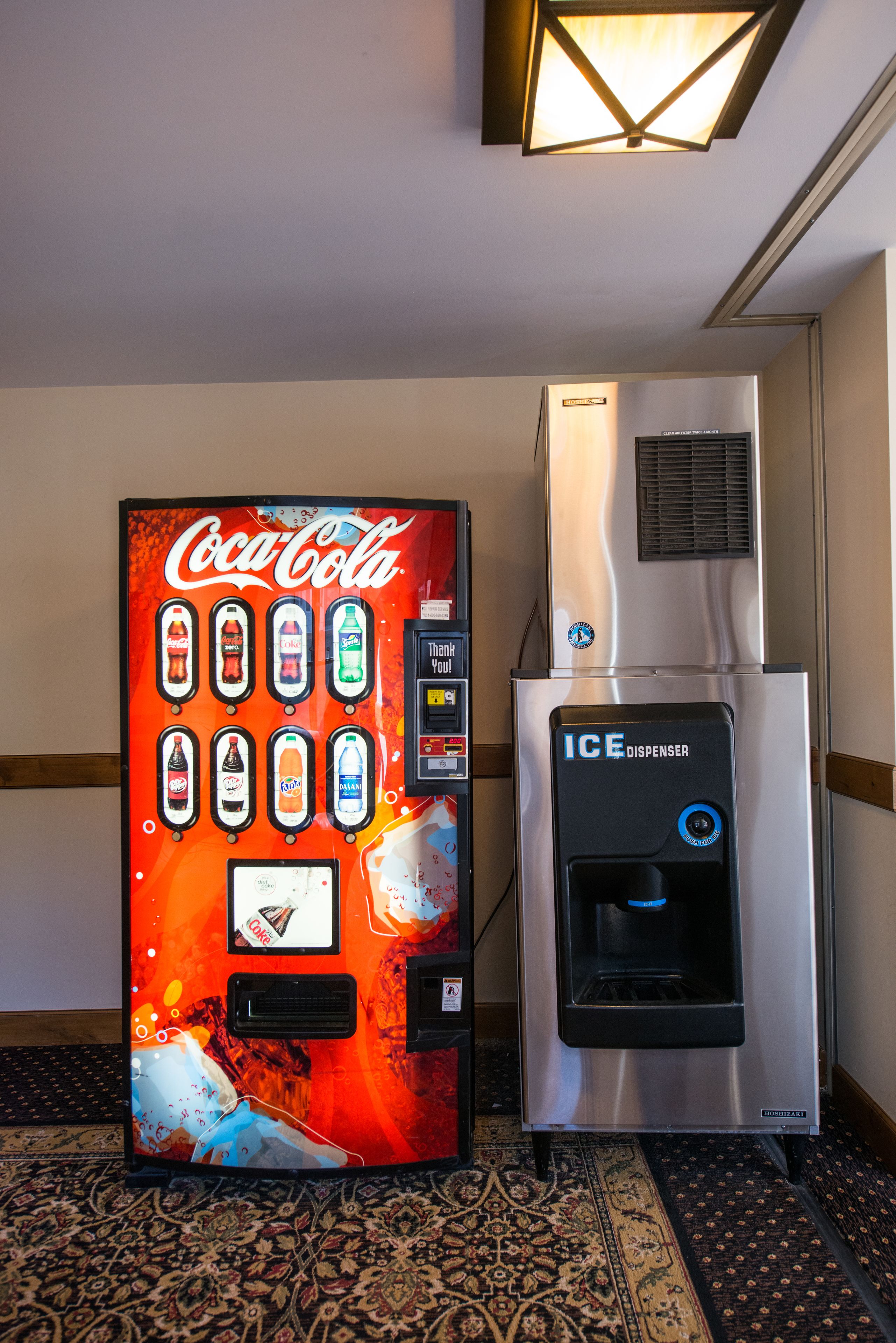 Un distributeur automatique de Coca-Cola et un appareil à glaçons dans le hall d’un hôtel.