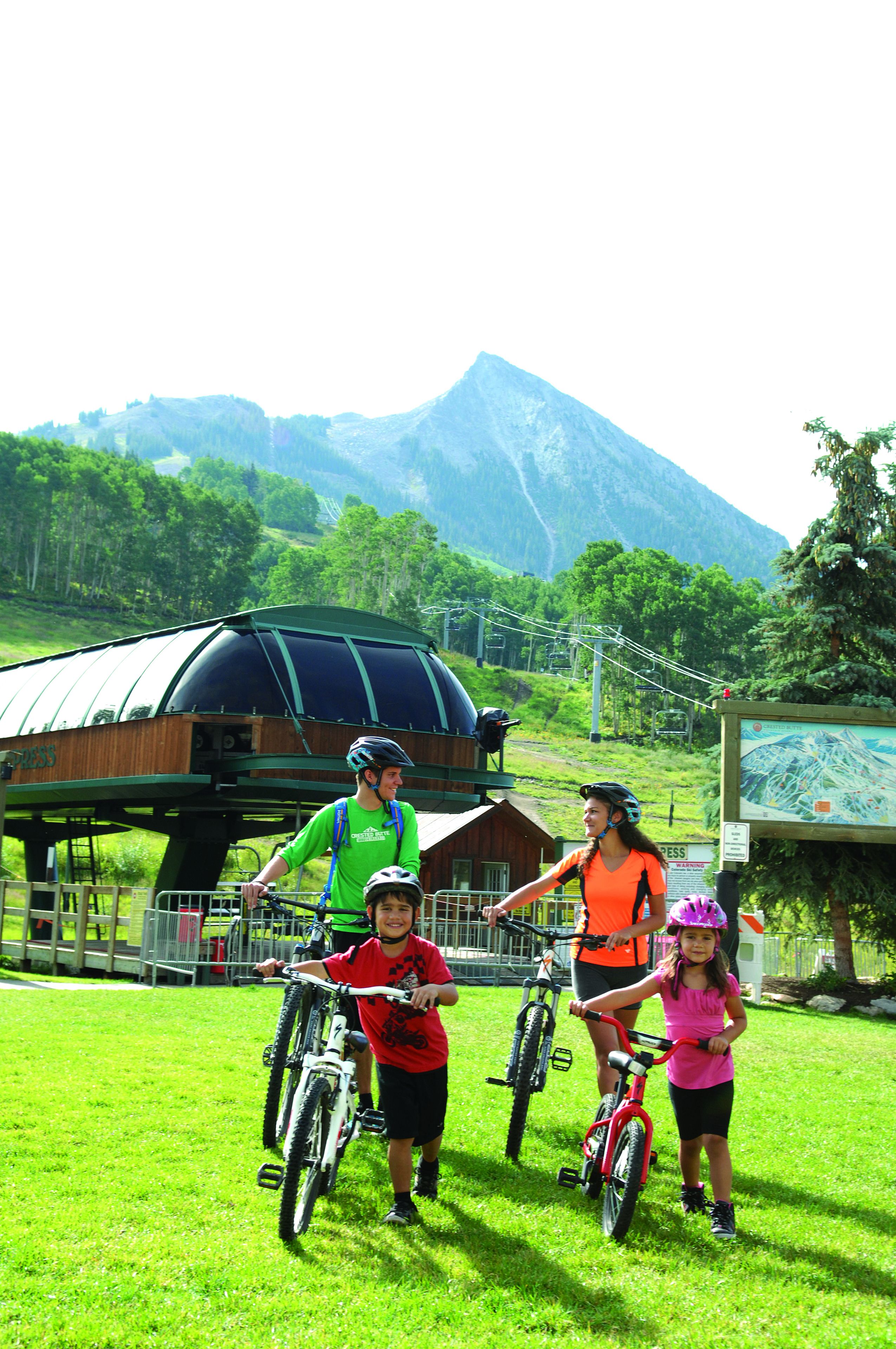A group of people on bicycles in a grassy area with a mountain backdrop.