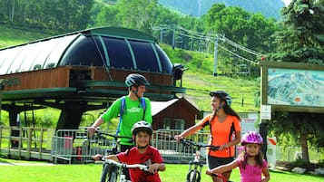 A group of people on bicycles in a grassy area with a mountain backdrop.