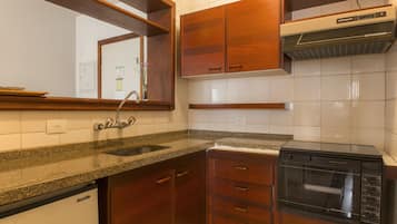 Una cocina con armarios de madera, encimera de granito, lavavajillas empotrado y microondas.