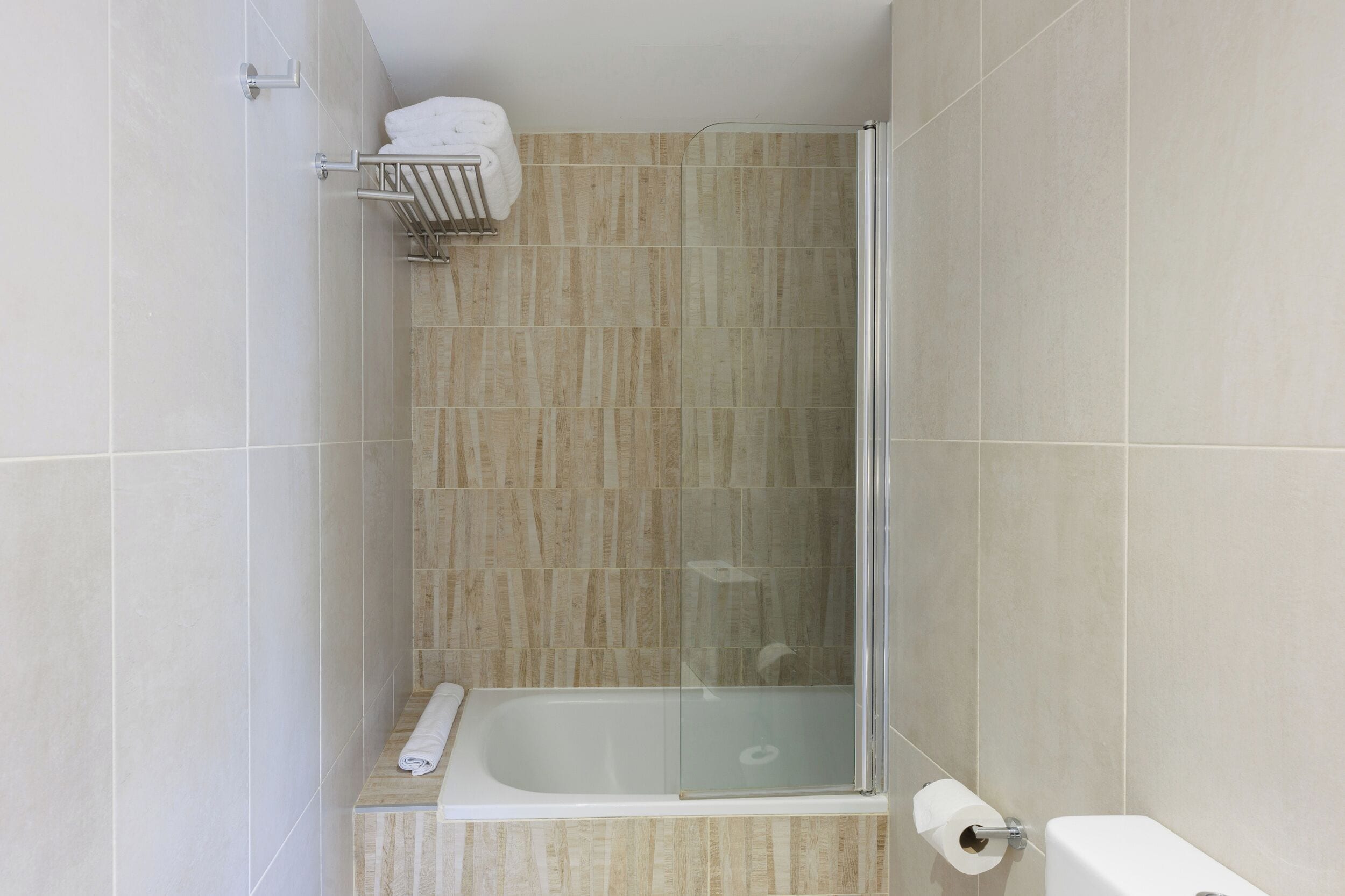 A bathroom with a glass-enclosed shower, a bathtub, and a toilet.