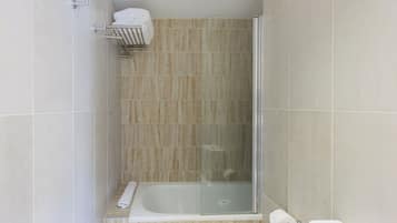 A bathroom with a glass-enclosed shower, a bathtub, and a toilet.