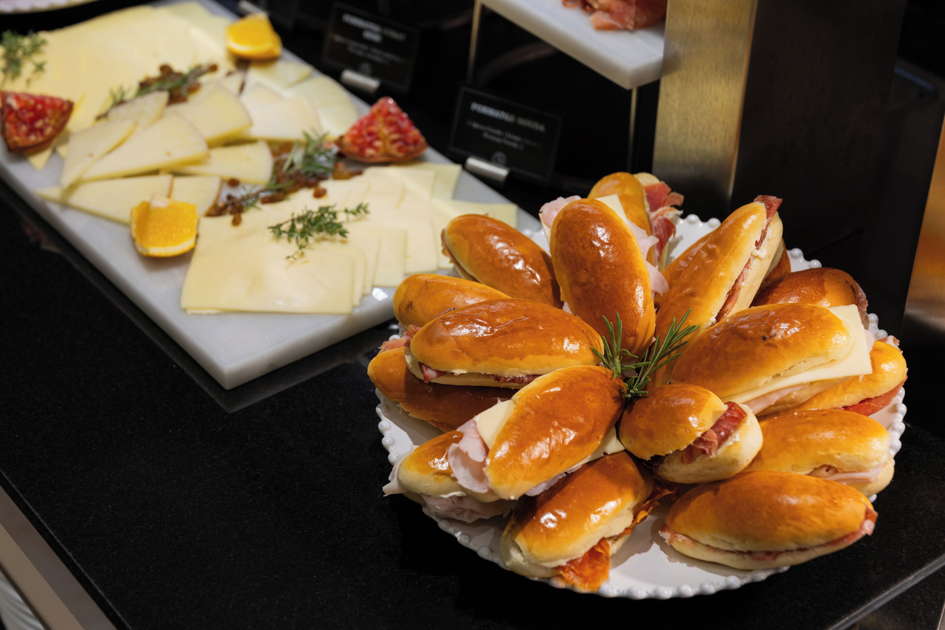 A buffet with various cheeses, fruits, and sandwiches.