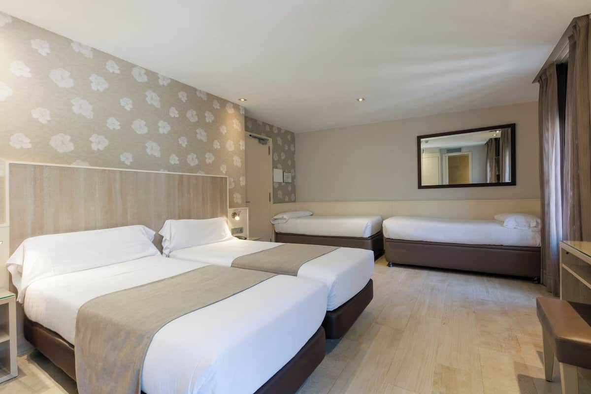 A hotel room with two beds, a wooden headboard, a mirror, and a wooden floor.
