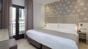 Habitación de hotel con una cama grande, un escritorio y vistas al balcón exterior.