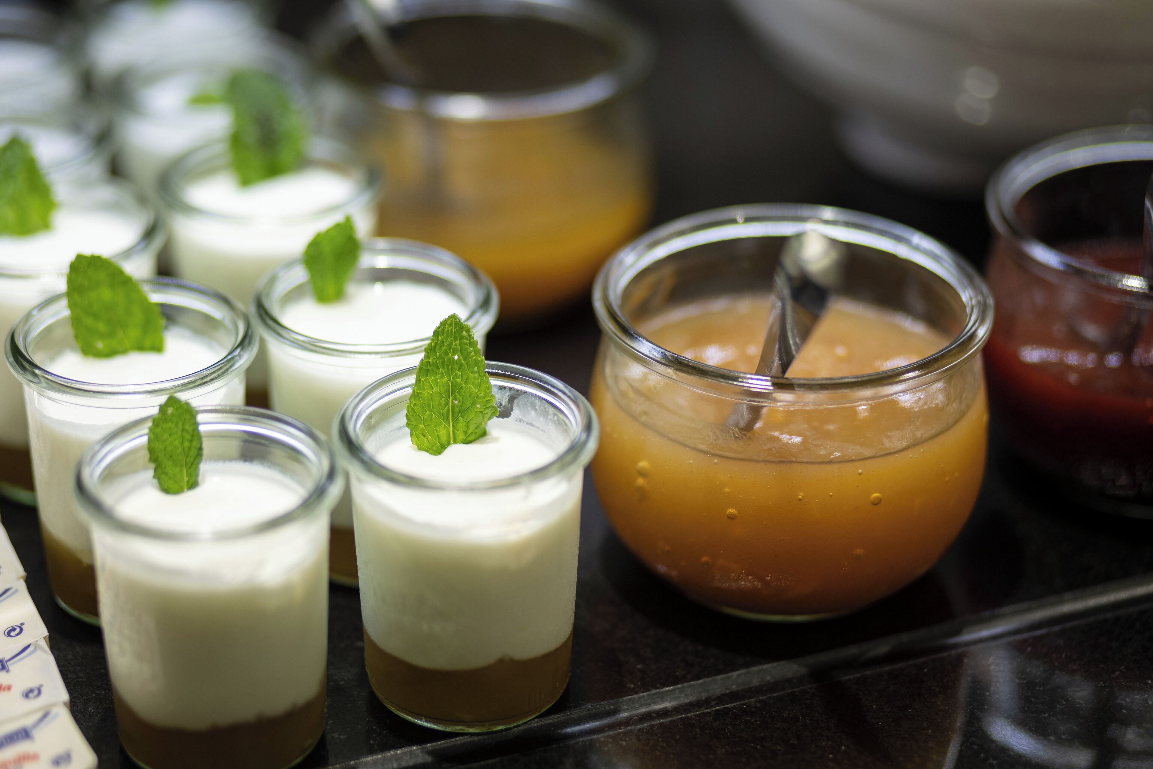 Une sélection de desserts présentés dans de petits récipients en verre, certains étant décorés d’une feuille de menthe.