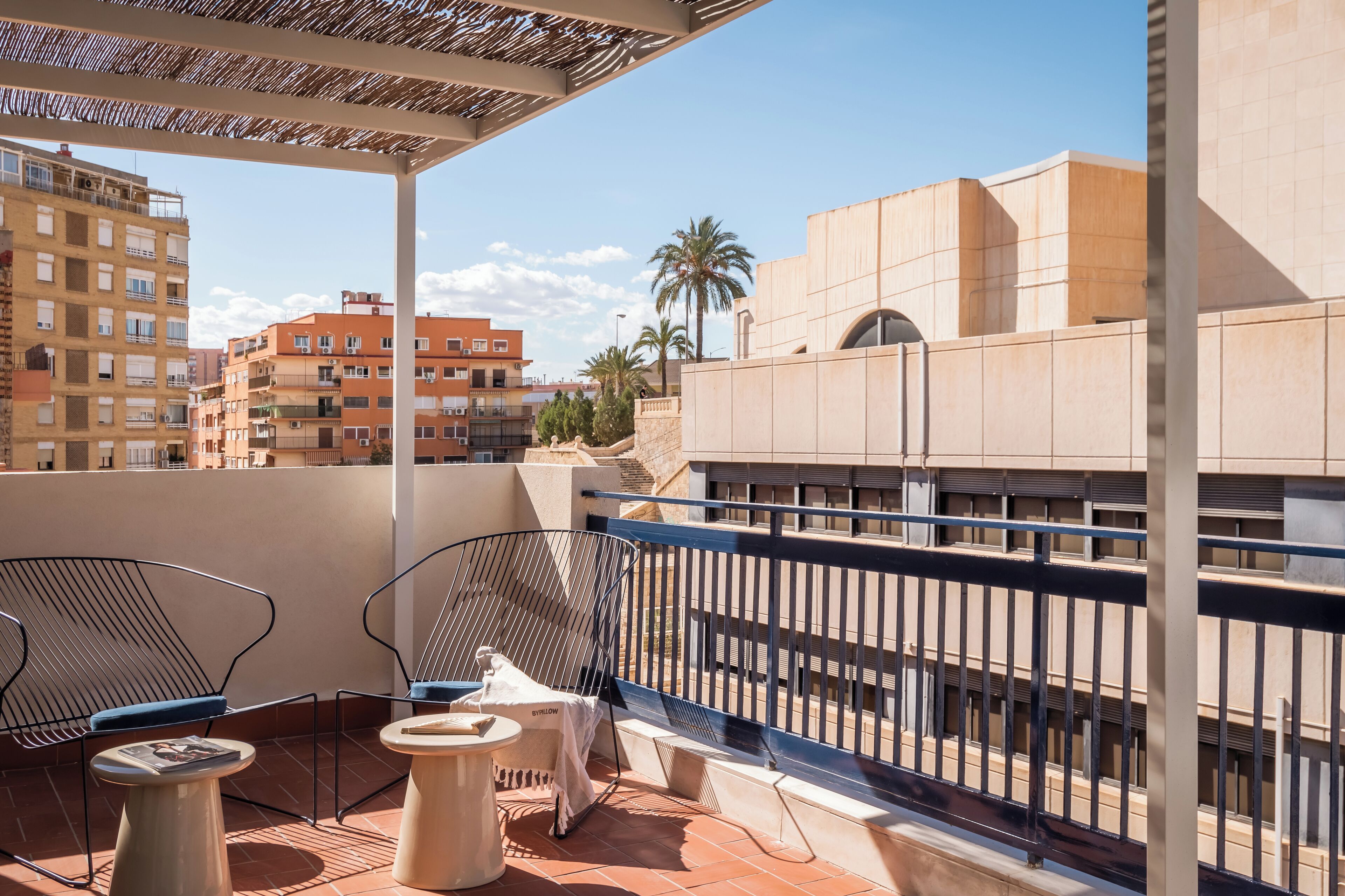 Un balcon doté d’une rambarde en métal, de deux chaises, d’une petite table et d’un espace abrité.