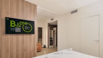 Une chambre d’hôtel avec un lit, une armoire, un miroir et une porte.