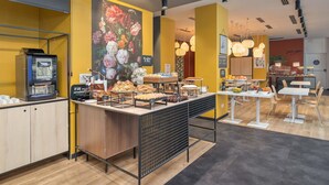 A café with a coffee machine, a variety of pastries, and a mural of flowers on the wall. - B&B Hotel Milano Central Station (Milan)