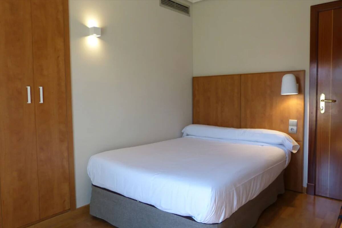Un dormitorio con una cama individual, un armario de madera y una mesita de noche con lámpara.