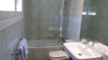 Une salle de bain moderne avec une douche à parois de verre, un lavabo blanc avec un miroir et des toilettes.