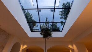 Un interior moderno con tragaluces, columnas en arco y una planta central.