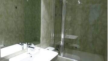 Un baño con dos lavamanos, ducha y cabina de ducha con mampara de vidrio.