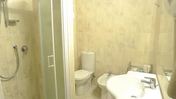 Een badkamer met douche, toilet en wastafel.