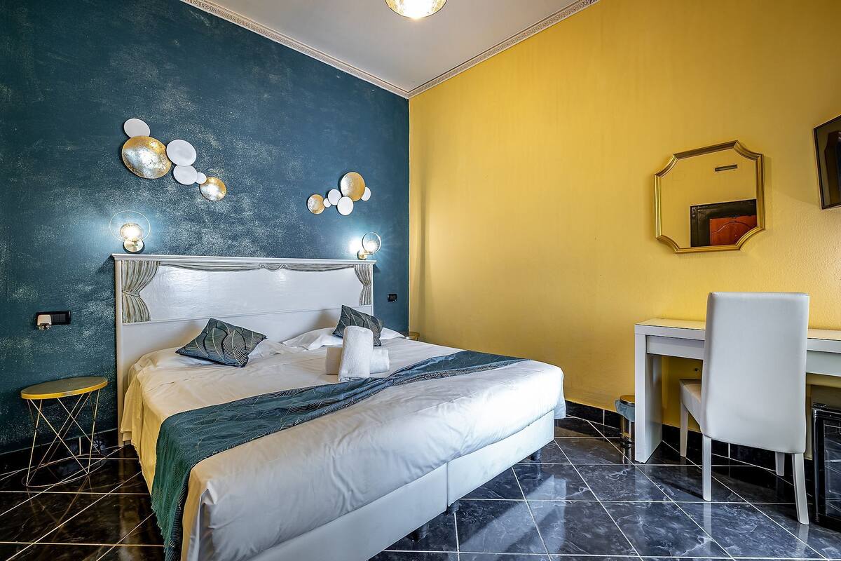 Una habitación de hotel con cama, mesita de noche, silla y escritorio.