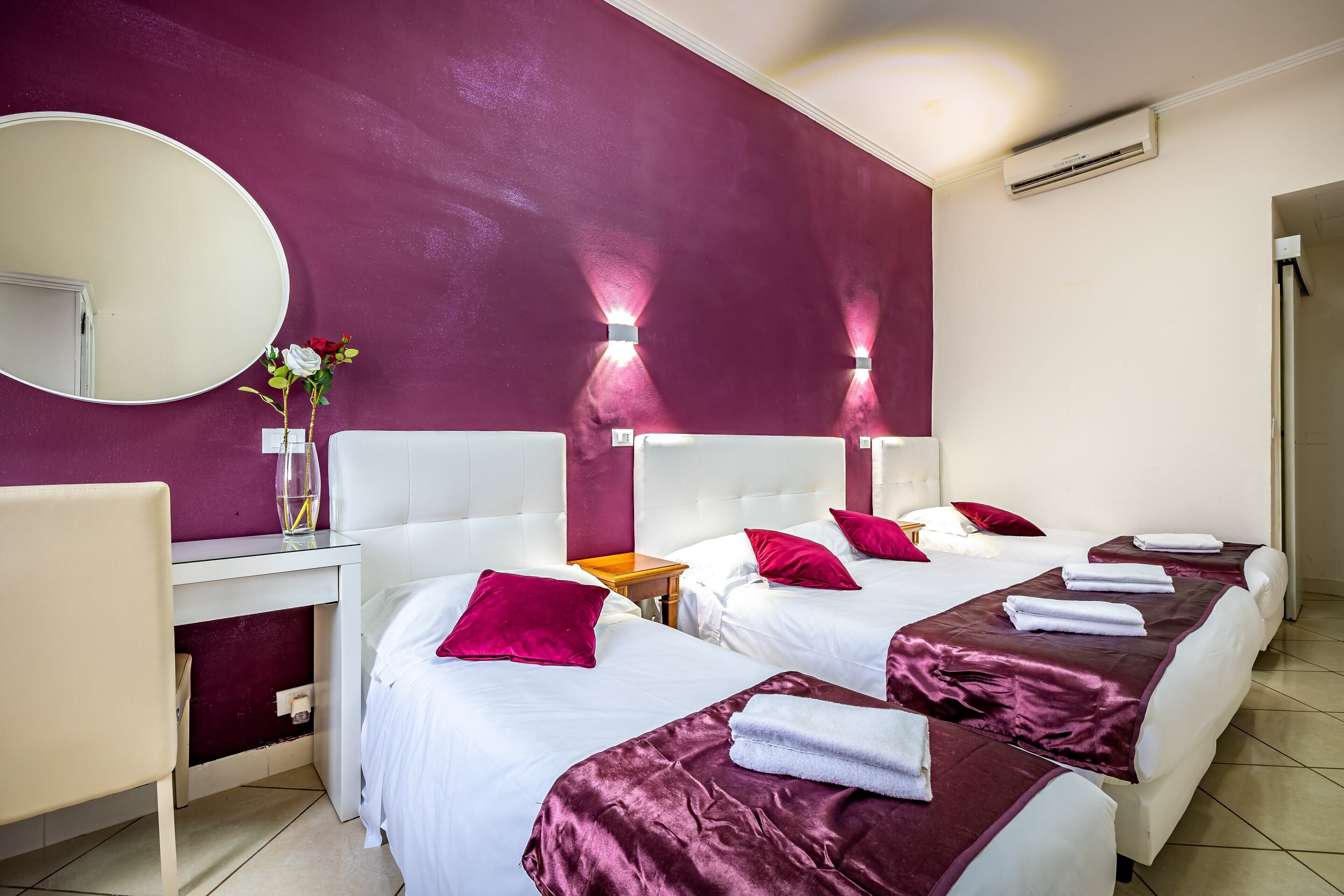 Ein Hotelzimmer mit zwei Betten, einem Schreibtisch, einem Stuhl, einem Spiegel und einer Klimaanlage.