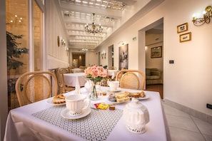 A dining area with a table set for breakfast, including pastries, tea, and a vase of flowers. - Hotel Veneto Firenze (Florence)