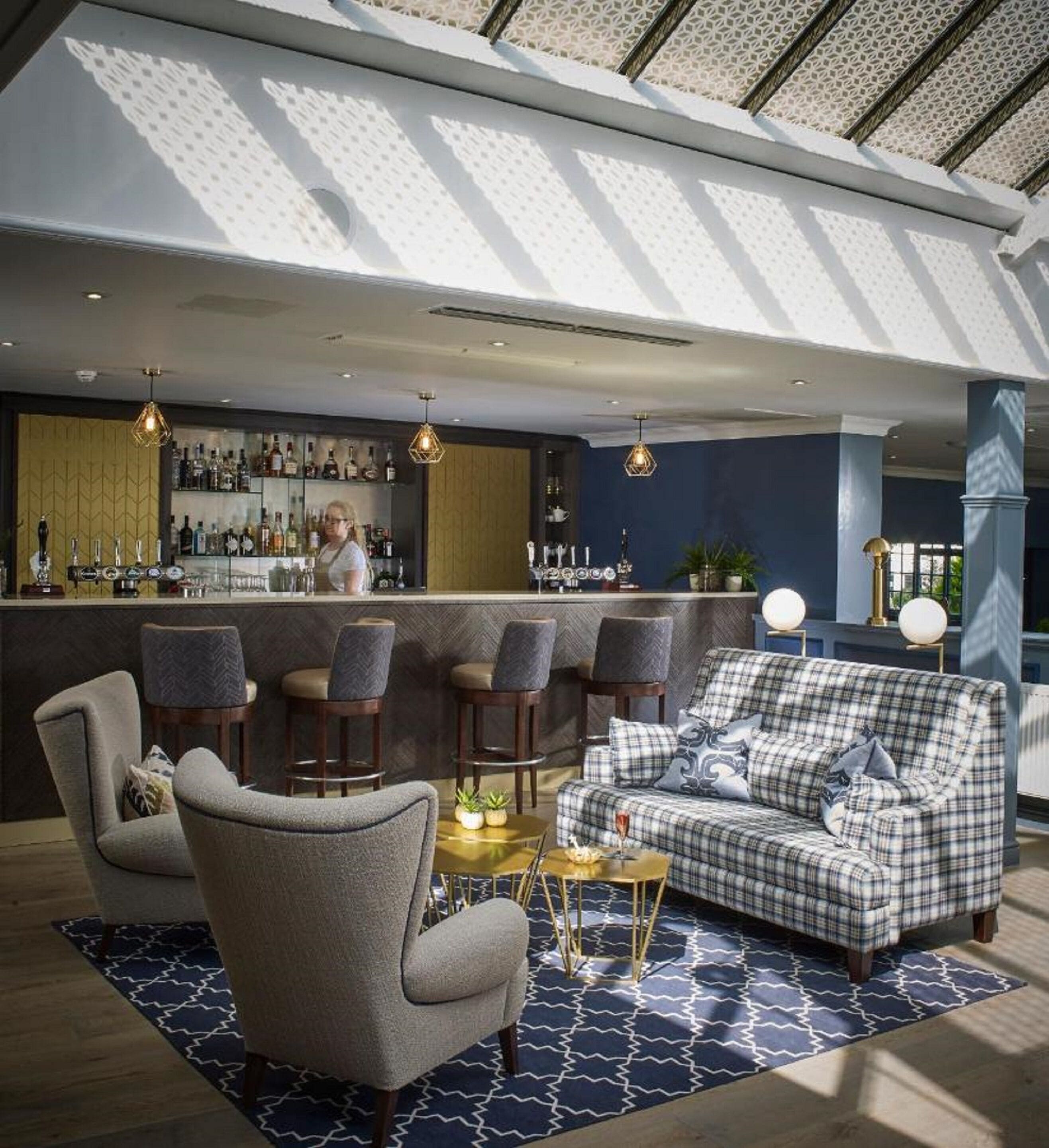 A bar area with a bar counter, multiple bar stools, and a sofa.