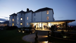 A large, multi-story building with a covered outdoor area and a well-lit entrance. - Tewkesbury Park (Tewkesbury)