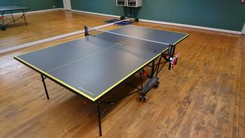 A ping pong table in a room with wooden flooring and green walls.