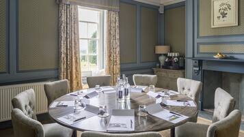A conference room with a round table, chairs, and various documents.