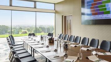Un salón de conferencias con una mesa grande, sillas y una pantalla que muestra datos de ventas nocturnas.