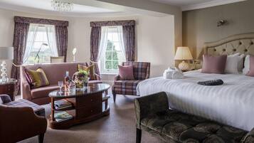 A hotel room with a large bed, a sofa, a chair, a coffee table, and a chandelier.