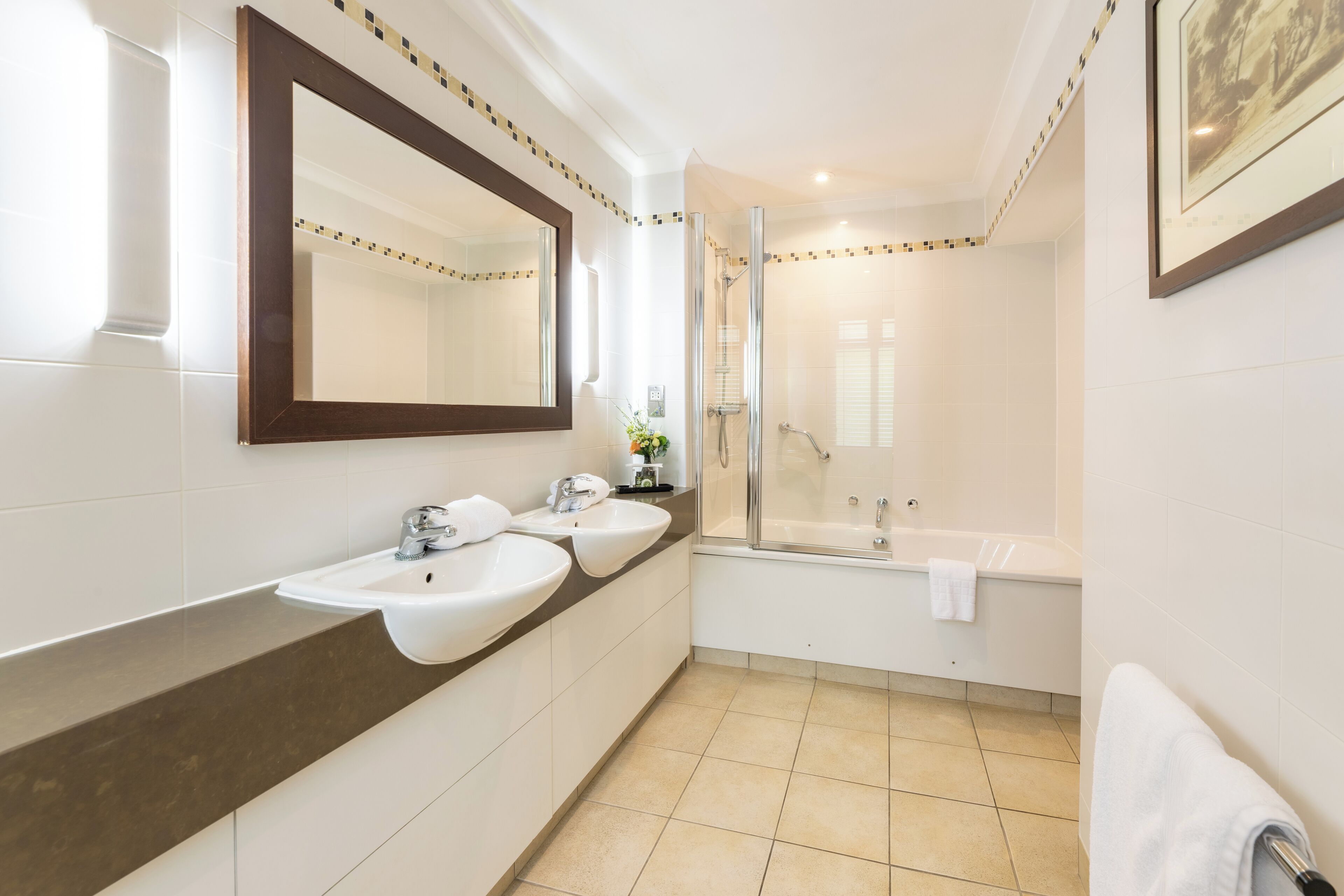 Een moderne badkamer met twee wastafels, een grote spiegel, een douche en een bad.